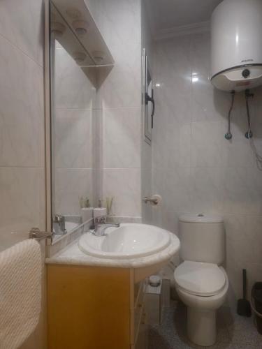 a white bathroom with a toilet and a sink at Beach view apartment in Cullera in Cullera