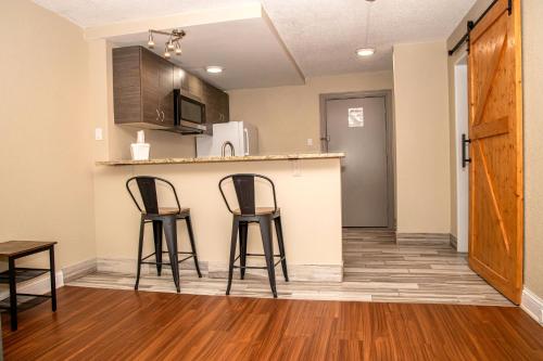 a kitchen with two bar stools and a counter at Days Inn and Suites by Wyndham Hammond, IN in Hammond