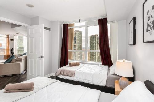 a bedroom with two beds and a window at Sky Retreat | 2BR-2BA High Floor | 180° City View in Mississauga