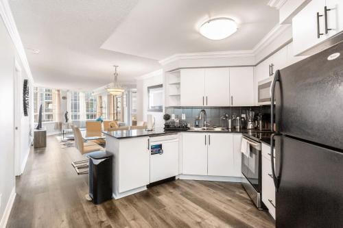 a kitchen with white cabinets and a black refrigerator at Sky Retreat | 2BR-2BA High Floor | 180° City View in Mississauga