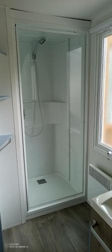 La salle de bains est pourvue d'une douche en verre et d'un lavabo. dans l'établissement Mobil Home Oléron, à La Celle-sous-Gouzon