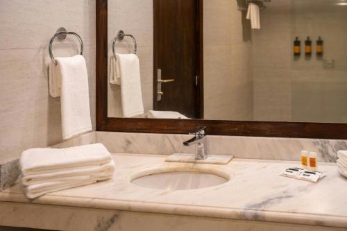 a bathroom with a sink and a mirror and towels at Yacht & Golf Club Paraguayo, a Tribute Portfolio Resort in Asuncion