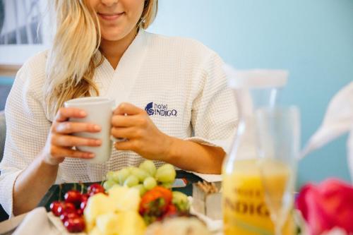 a woman sitting at a table holding a cup of juice at Hotel Indigo Orange Beach - Gulf Shores by IHG in Gulf Shores