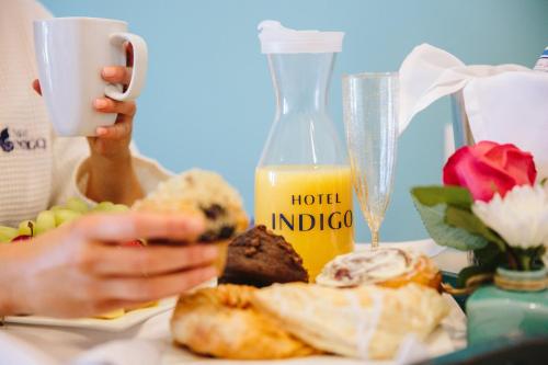 a person taking a picture of a table with food and orange juice at Hotel Indigo Orange Beach - Gulf Shores by IHG in Gulf Shores