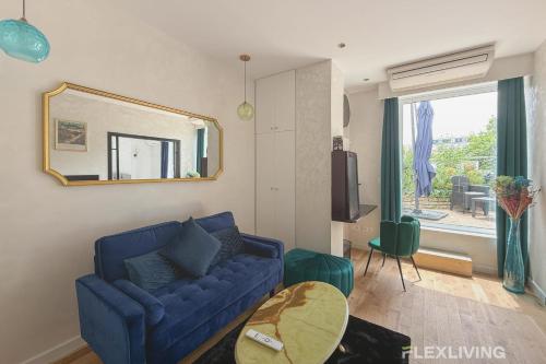 un salon avec un canapé bleu et un miroir dans l'établissement Bright apartment with garden close to the metro, à Paris