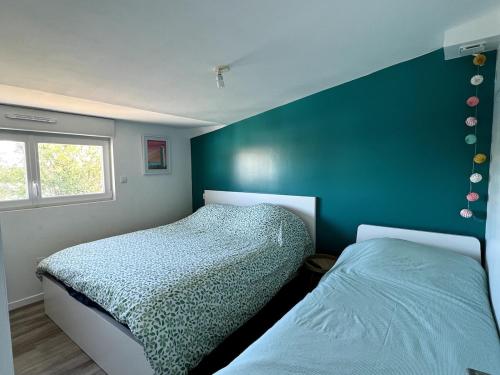 - une chambre avec 2 lits et un mur vert dans l'établissement Maison charmante avec piscine - 6 personnes - proche mer, à Saint-Gilles-Croix-de-Vie