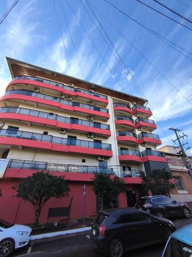 a tall building with cars parked in front of it at Dpto a pasos de la playa San José in Encarnación