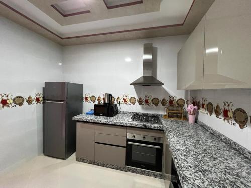 a kitchen with a stove and a refrigerator at Résidence Assalam - en bord de mer in Azla