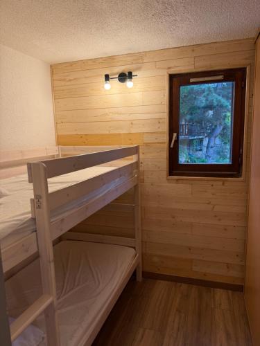 Ce lit superposé se trouve dans un dortoir en bois doté d'une fenêtre. dans l'établissement Résidence Alpina 1, à Les Deux Alpes
