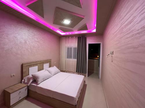 a bedroom with a bed with a pink lighting at Résidence Assalam - en bord de mer in Azla