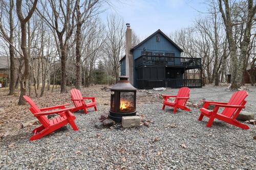 a group of red chairs and a fireplace in front of a house at Moose Tracks Cabin Hot Tub 1 Mile To Lake in Lake Harmony