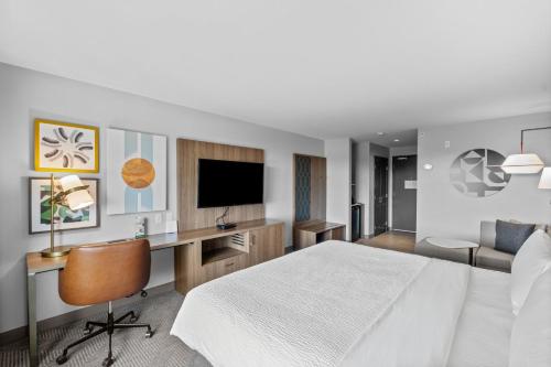 a hotel room with a bed and a desk with a television at Holiday Inn Hotel & Suites Surrey East - Cloverdale by IHG in Surrey