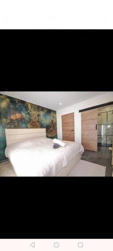 - une chambre avec un grand lit blanc orné d'une peinture murale dans l'établissement Villa Moderne Piolenc, à Piolenc