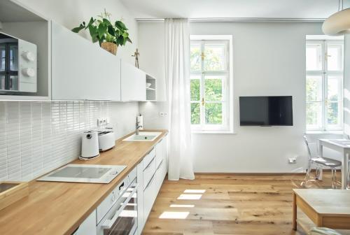 a kitchen with white cabinets and a wooden floor at Apartmány VIENNA in Mikulov