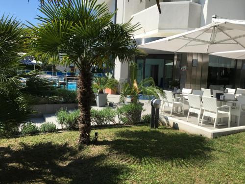 a palm tree in front of a building with an umbrella at Hotel Bellevue in Lignano Sabbiadoro