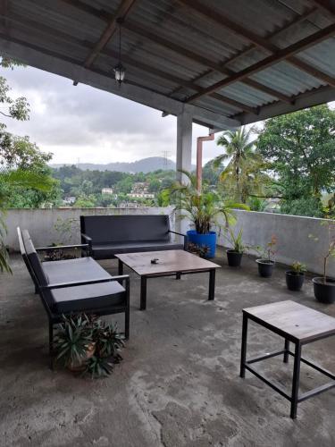 a patio with a couch and tables and potted plants at Aquahills in Kandy