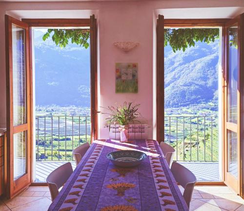 TresivioにあるCasa il Glicine Valtellinaのテーブルと大きな窓のあるダイニングルーム