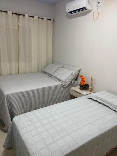 two beds in a small room with a window at casa de veraneio jalapão in São Félix do Tocantins