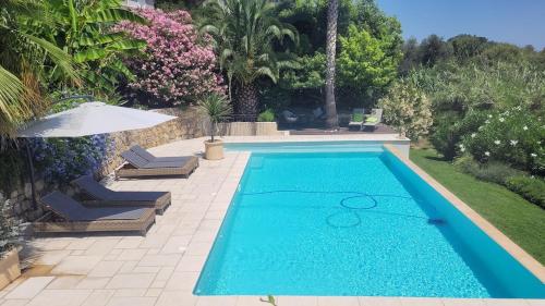 une piscine avec deux chaises et un parasol dans l'établissement Villa 06, à Le Tignet
