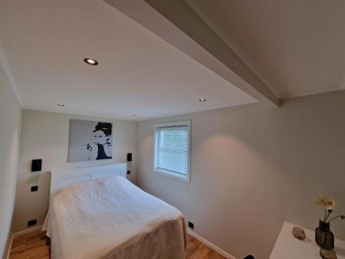 a bedroom with a white bed and a window at Comfortable Apartment Sleeps 4 Near Kristiansand City Center in Kristiansand