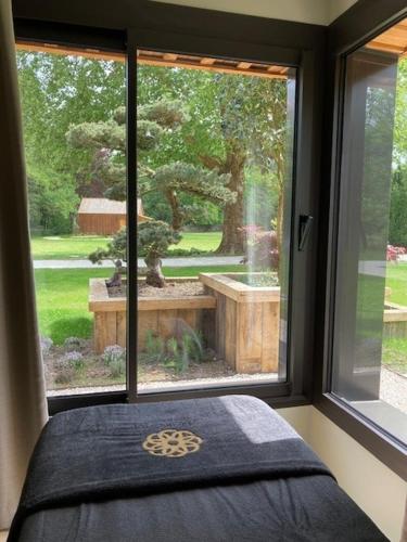 a bedroom with a window looking out at a tree at Le Moulin de l'Ortille & SPA in Compiègne