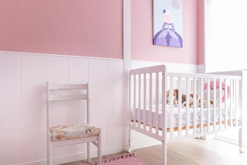 a pink and white nursery with a crib and a chair at Mi casita del norte a 150 m de la playa in Mogro