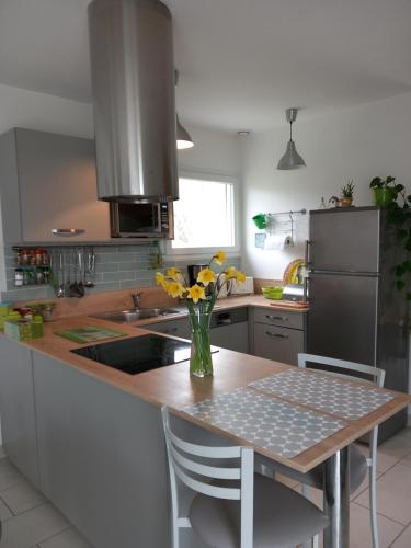 une cuisine avec une table avec un vase de fleurs dessus dans l'établissement Entre terre et mer, à La Celle-sous-Gouzon