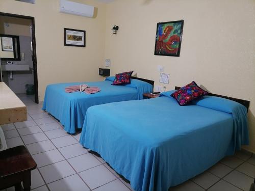 two beds in a room with blue sheets at Hotel - Museo Xibalba in Palenque