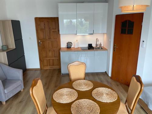 a room with a table and chairs and a kitchen at Promyczek in Krynica Morska