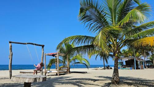 a person sitting on a swing on a beach at Playas De Casa Grande in Santa Marta