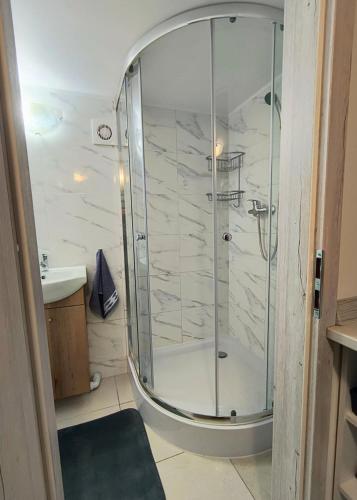 a shower with a glass door in a bathroom at Pod Lasem Kwatery Pracownicze in Gollnow