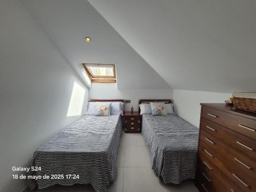 a attic bedroom with two beds and a dresser at Lar BCN in Pobra do Caramiñal