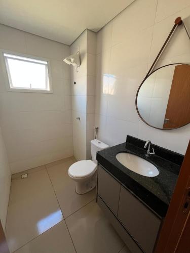 a bathroom with a toilet and a sink and a mirror at Apto Novo com Ar e Wi-Fi Perto da UFU Monte Carmelo in Monte Carmelo