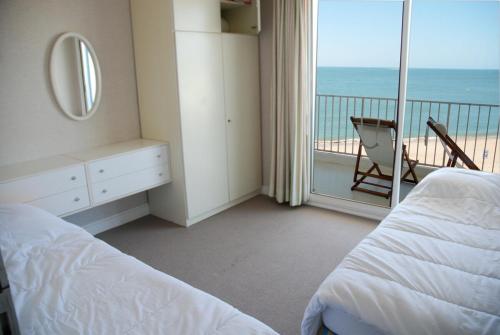 a bedroom with a bed and a balcony with the ocean at Le Vintage By Tranquil at Home in Pornichet