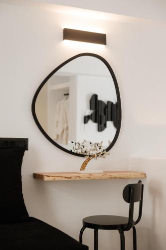 a round mirror on a wall next to a chair at Commercio Suites Santorini in Emporio Santorini