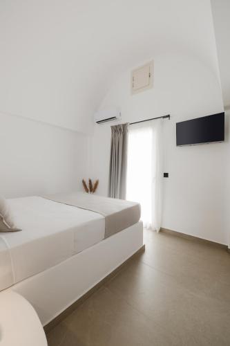 a white bedroom with a bed and a tv at Commercio Suites Santorini in Emporio Santorini
