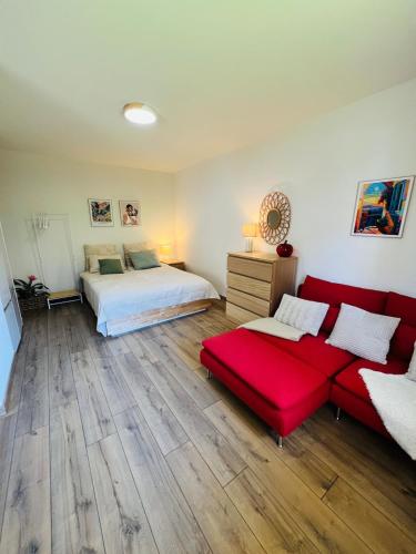 une chambre avec un lit et un canapé rouge dans l'établissement Modern Loft Basel Airport ArtBasel, à Saint-Louis