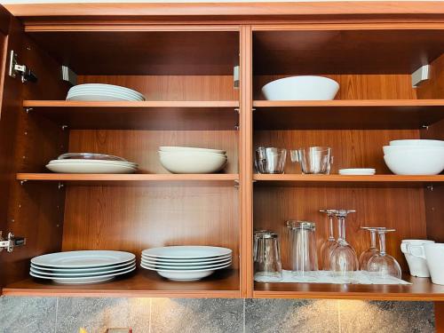 a wooden cabinet with plates and dishes in it at Modern Loft Basel Airport ArtBasel in Saint-Louis