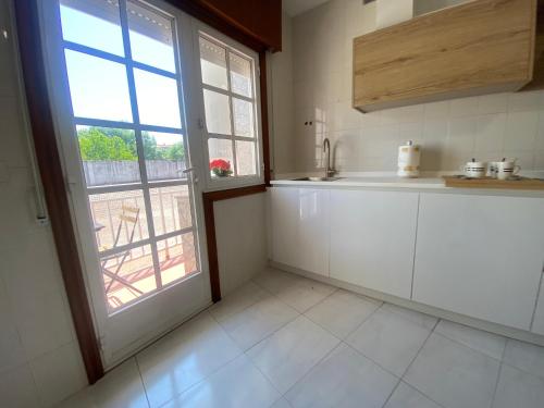 a kitchen with white cabinets and a large window at A un Paso in Caldas de Reis