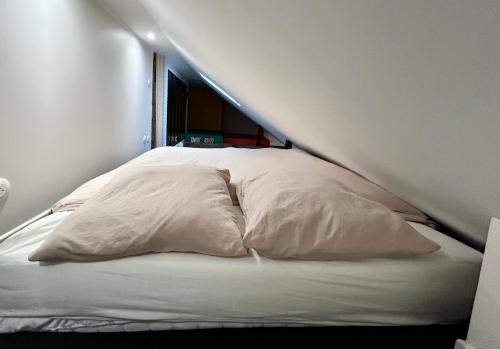 un lit avec des draps blancs et des oreillers dans une chambre dans l'établissement Le Refuge Saint Sauveur, à Caen