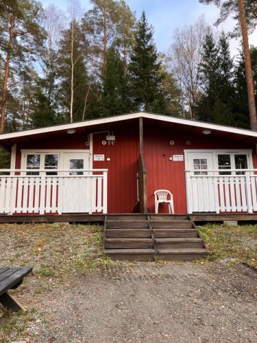 a red cabin with a chair in front of it at Bredsands camping och bad- Bredsandsstugor in Enköping