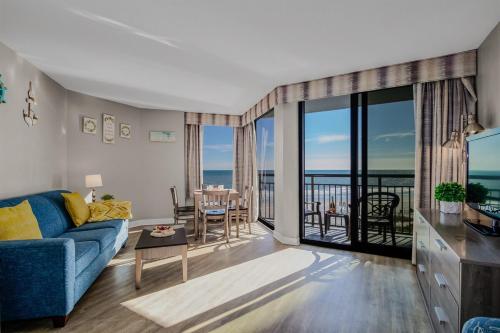 a living room with a blue couch and a balcony at Calming Oceanfront Suite, Dogs OK! 410 in Myrtle Beach