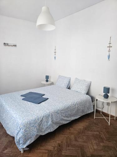 a bedroom with a bed with a blue blanket and two tables at Lagos Haven Guesthouse in Lagos