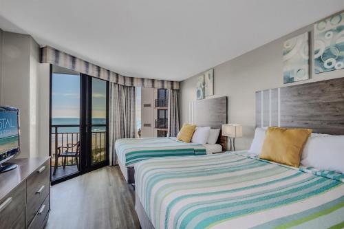 een hotelkamer met twee bedden en een balkon bij Winter Rates! Calming Oceanfront Suite, Dogs OK! 410 in Myrtle Beach
