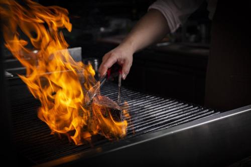 a person is cooking food on a grill with flames at Regent Chongqing - Complimentary 1st round mini bar daily in Chongqing
