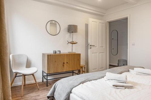 a bedroom with a bed and a chair and a mirror at Ferienwohnung Pellwormer Küstenkind in Pellworm