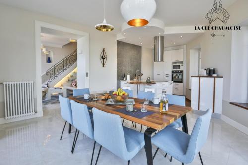 une cuisine et une salle à manger avec une table en bois et des chaises bleues dans l'établissement Villa des Palmiers, à Les Sables-dʼOlonne