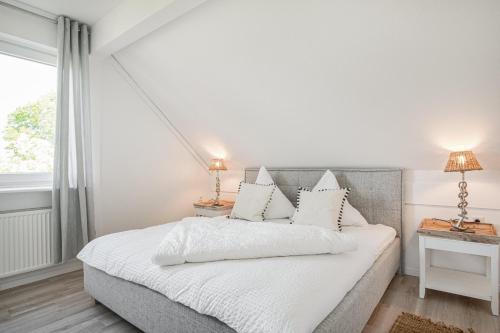 a bedroom with a bed with white sheets and a window at Ferienwohnung Deichblick Quartier Pellworm in Pellworm