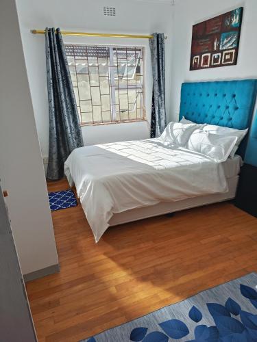 a bedroom with a bed with a blue headboard and a window at PEACEFUL SLEEP lodge in Goodwood