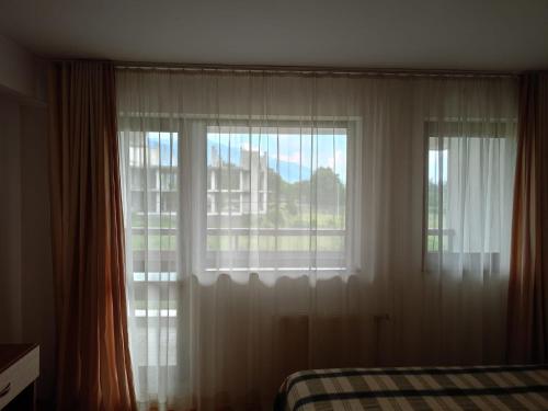 een slaapkamer met een raam met witte gordijnen en een bed bij Mountain Paradise 1 - 2 Bedroom - Large apartment in Bansko